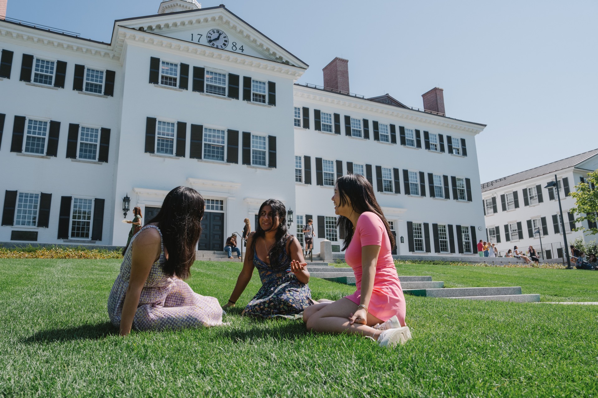 Three students sitting on the grass