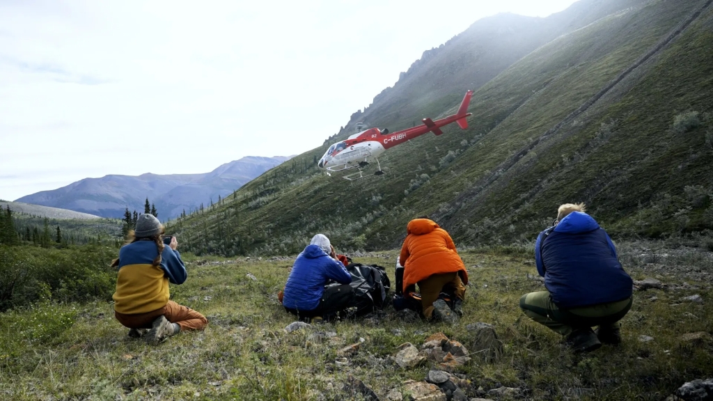 People watching a helicopter in the mountains